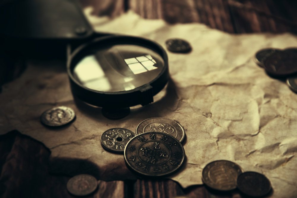 Coins and a magnifiying glass on top of parchment paper