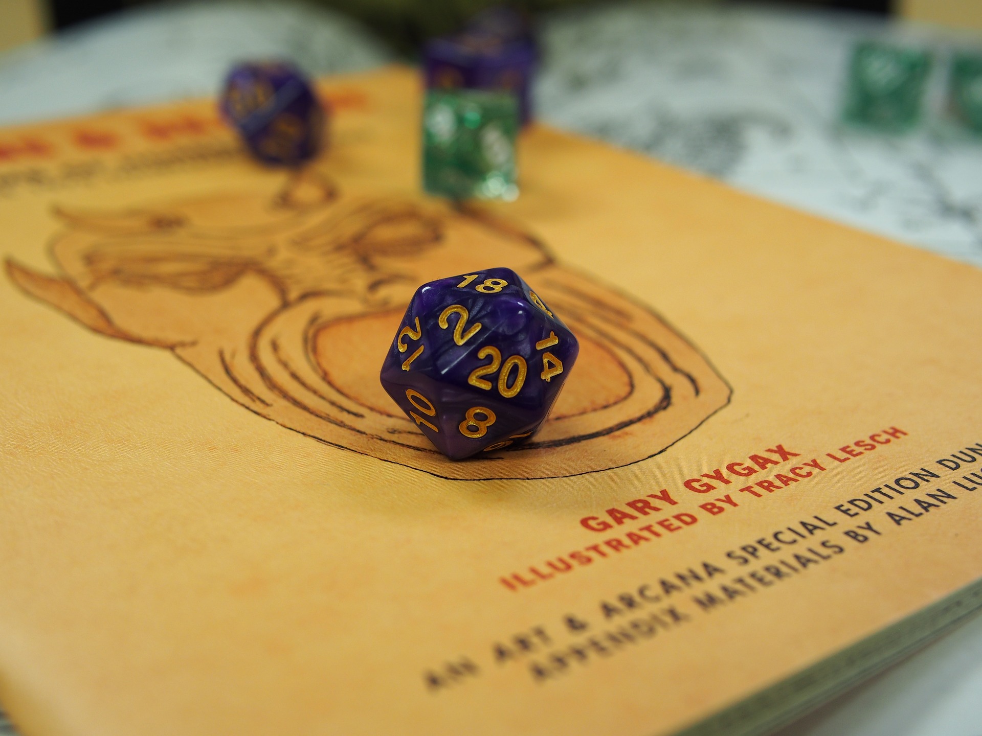 Close-up of a Dungeons & Dragons book featuring artwork and the name Gary Gygax. A purple twenty-sided die (d20) with gold numbers, showing a 20, rests on top of the book.