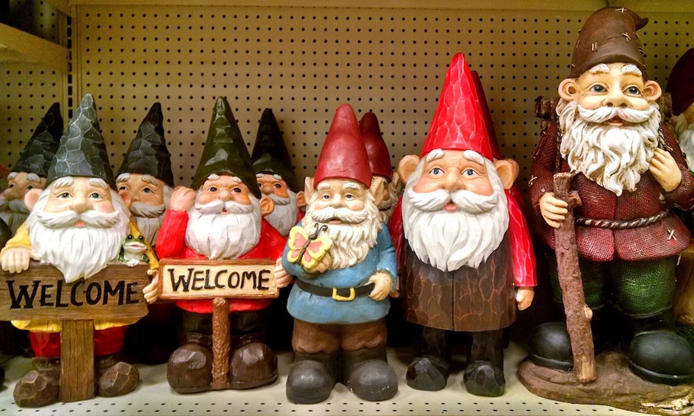 A shelf of garden gnomes, many of them holding welcome signs